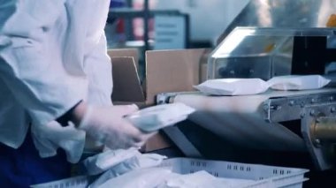 Fabrika çalışanı taşıyıcıdan beyaz paketler topluyor.