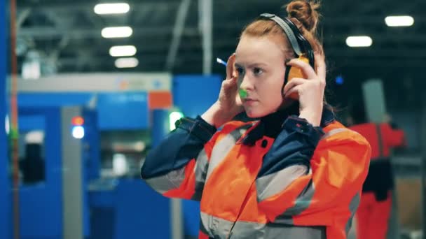 Ingeniera femenina se pone auriculares y comienza a operar una consola — Vídeos de Stock