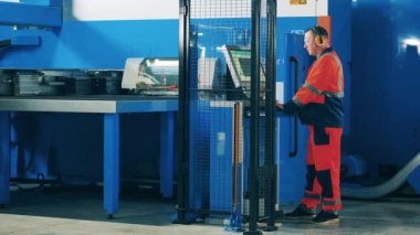 Metal oluşturma makinesi kullanan fabrika işçisi