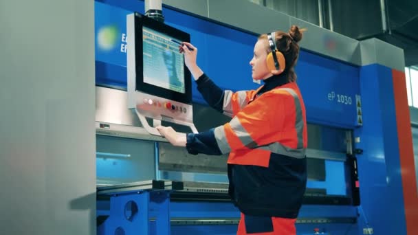 Workwoman operating a metal bending machine through a screen — Stock Video