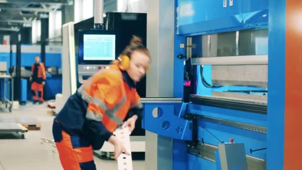 Female worker placing aluminum part into a machine — Stock Video