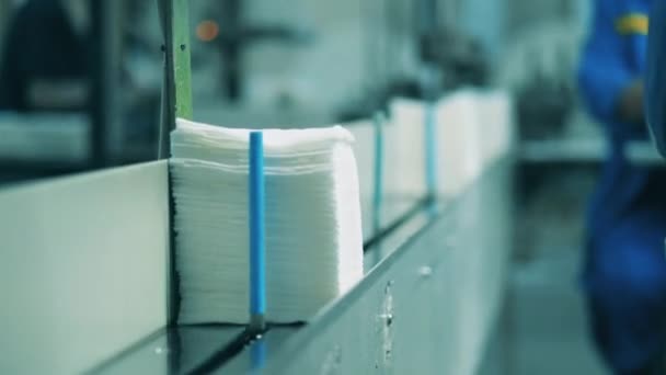Пачка бумажных салфеток помещается на конвейер рабочим завода — стоковое видео