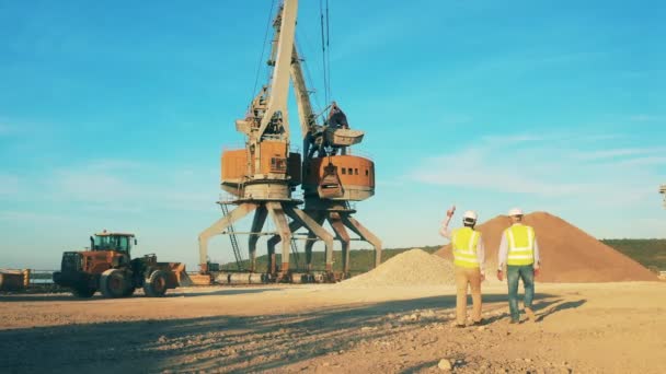 有机械装载机和两名工程师在谈话的采石区 — 图库视频影像