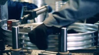 Özel bir makine kullanarak bisiklet jantlarını kesen bir fabrika işçisi.