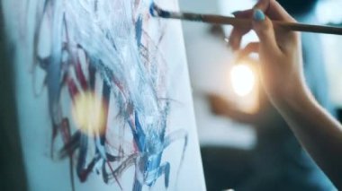 Kadın eli tuvale resim çizmek için fırça kullanıyor.