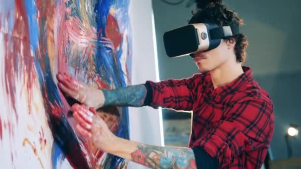 Um homem está usando óculos VR para pintar um quadro com as mãos — Vídeo de Stock