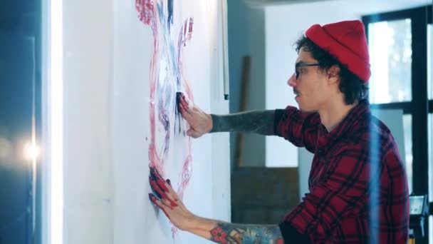 Young man is painting a picture with his hands — Stock Video