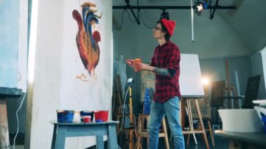 Genç adam onu boyarken resmini inceliyor.