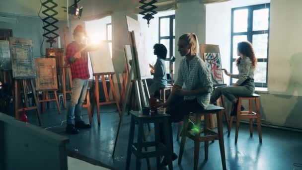 Un uomo sta insegnando arte a un gruppo di studenti che stanno disegnando — Video Stock