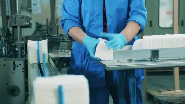 Женщина-работница завода кладет на конвейер салфетки из белой бумаги — стоковое видео