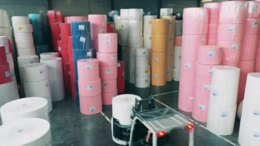 Büyük bir kağıt rulosunu taşımak için forklift kullanan bir fabrika işçisi.