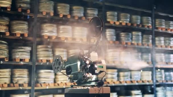 Filmarkiv med en projektor som arbetar i rök. Retrofilm, vintageteknik koncept. — Stockvideo