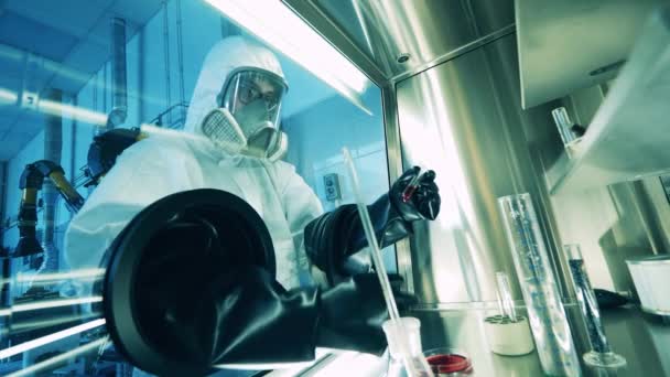 Specialist in een hazmat pak maakt gebruik van een laboratoriumkast testen sondes — Stockvideo