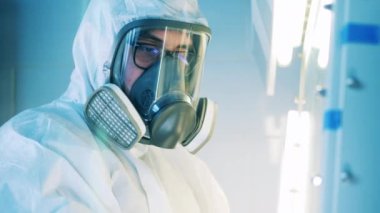 Tehlikeli madde giysisi giyen bir erkek uzman laboratuarda çalışıyor.