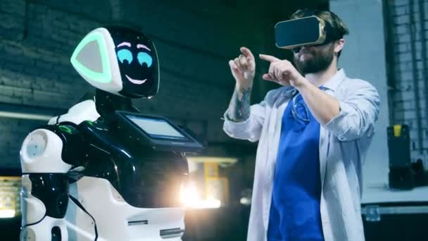 Männlicher Programmierer in VR-Brille kommuniziert mit Roboter — Stockvideo