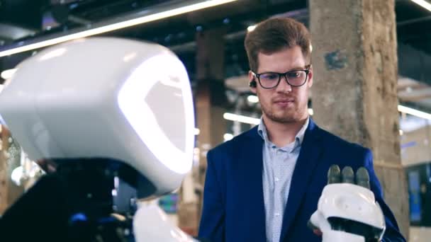 A man is being surprised while touching robots hand — Stock Video