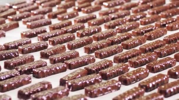 Un montón de barras de chocolate dulces que se mueven a lo largo del transportador de fábrica — Vídeo de stock