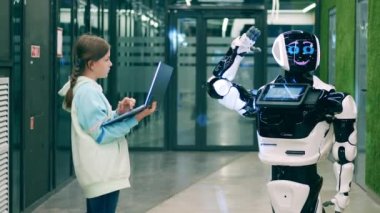 Bir kız, bir droidi dizüstü bilgisayarıyla yönetiyor.