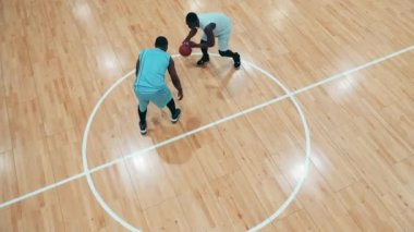 İki Afrikalı basketbolcunun antrenman yaptığı bir spor salonu.