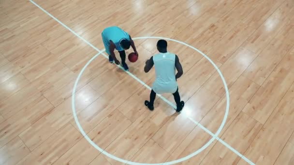 Ovanifrån av två afrikanska etniska spelare som tränar basket i gymmet. Basketspelare i mörker. — Stockvideo