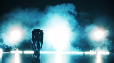 Bir adam karanlık bir odada basketbol topuyla pratik yapıyor.