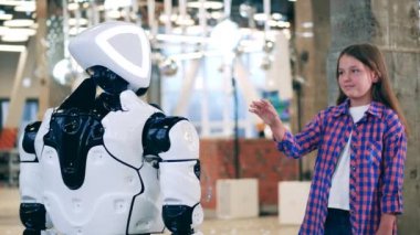 Neşeli kız bir droidin eline dokunuyor.