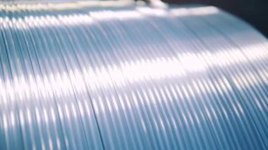 Parlak gümüş elektrik kablosu makaradan sarkıyor. Kapat.