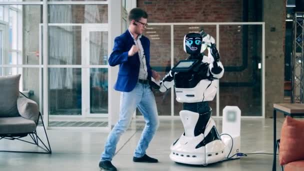 Biznesmen tańczy z nowoczesnym robotem w holu. Sztuczna inteligencja, innowacje robotyczne, koncepcja cyborga. — Wideo stockowe