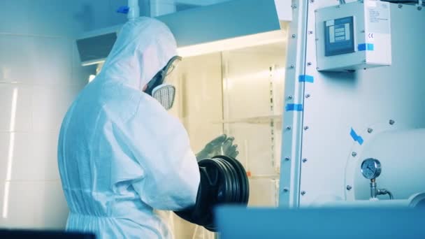 Lavoratore di laboratorio in una tuta hazmat sta utilizzando un armadio a vuoto per la ricerca — Video Stock