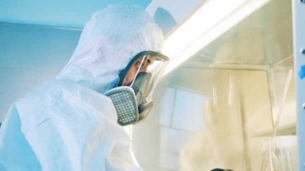 Male scientist in a hazmat suit is working with a vacuum cabinet — Stock Video