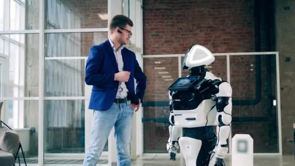 Un hombre con traje de negocios está hablando con un cyborg en un pasillo. — Vídeo de stock