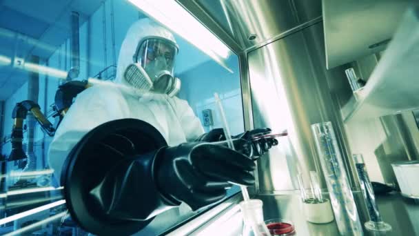 Επιστήμονας με στολή επικίνδυνων υλικών χρησιμοποιεί ένα ντουλάπι κενού για ανάλυση. — Αρχείο Βίντεο