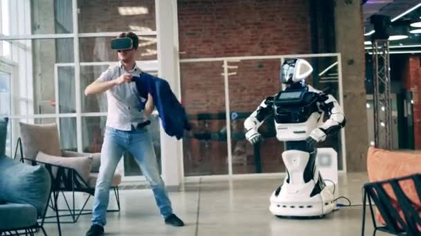 Conceito de comunicação humano e robô. Empresário está usando óculos VR enquanto dança ao lado de um cyborg — Vídeo de Stock