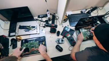 Uzman gurup dizüstü bilgisayarları üst görüntüde tamir ediyor.