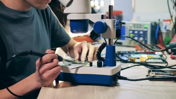 Repairman is using a microscope while fixing a circuit — Stock Video