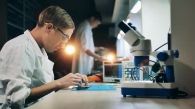 Cep telefonunu bir tamirci tamir ediyor.