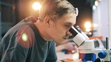 Tamirci mikroskop altında bir devreyi inceliyor.