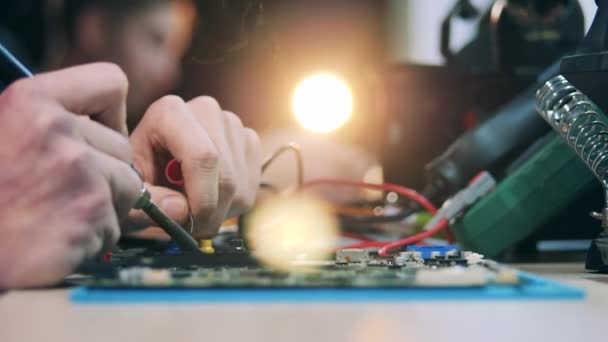Reparaties handen tijdens het solderen van een circuit in een close-up — Stockvideo