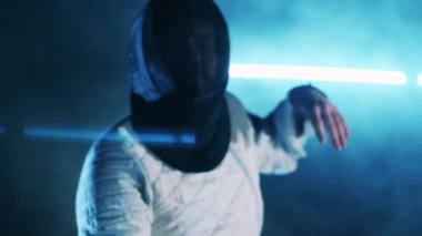 Koruyucu maskeli eskrimci folyoyla pratik yapıyor.