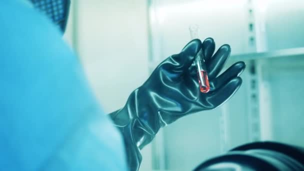 Tubo de ensayo en las manos de un trabajador de laboratorio que usa guantes — Vídeo de stock