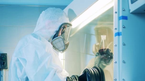 Pracovník laboratoře sleduje tekutý vzorek v laboratorní skříni. — Stock video