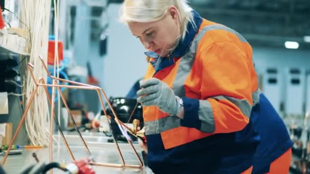 Travailleuse soudant de petits tuyaux ensemble dans une usine de fabrication de réfrigérateur — Video