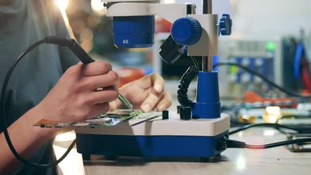 Circuit is getting soldered by a repairman using a microscope — Video