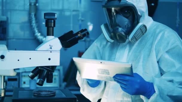 Specjalista laboratoryjny operuje tabletem i mikroskopem — Wideo stockowe