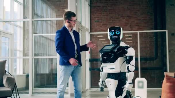 Robot moderno y un hombre de negocios están teniendo una conversación. Concepto de comunicación humana y robótica. — Vídeo de stock