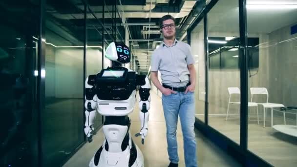 Liikemies juttelee kyborgin kanssa kävellessään käytävää pitkin. — kuvapankkivideo