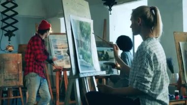 Sanat öğrencileri öğretmenleriyle konuşurken resim yapıyorlar.