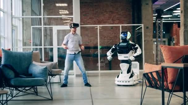 Salón de negocios con un bailarín en gafas VR y un robot — Vídeo de stock