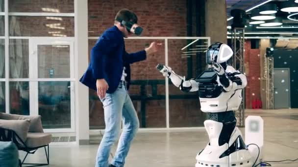 Um homem de óculos RV está a dançar com um robô. Inteligência artificial, inovação em robótica, conceito de cyborg. — Vídeo de Stock