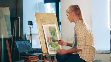 Bir kadın internet dersi sırasında resim yapıyor.